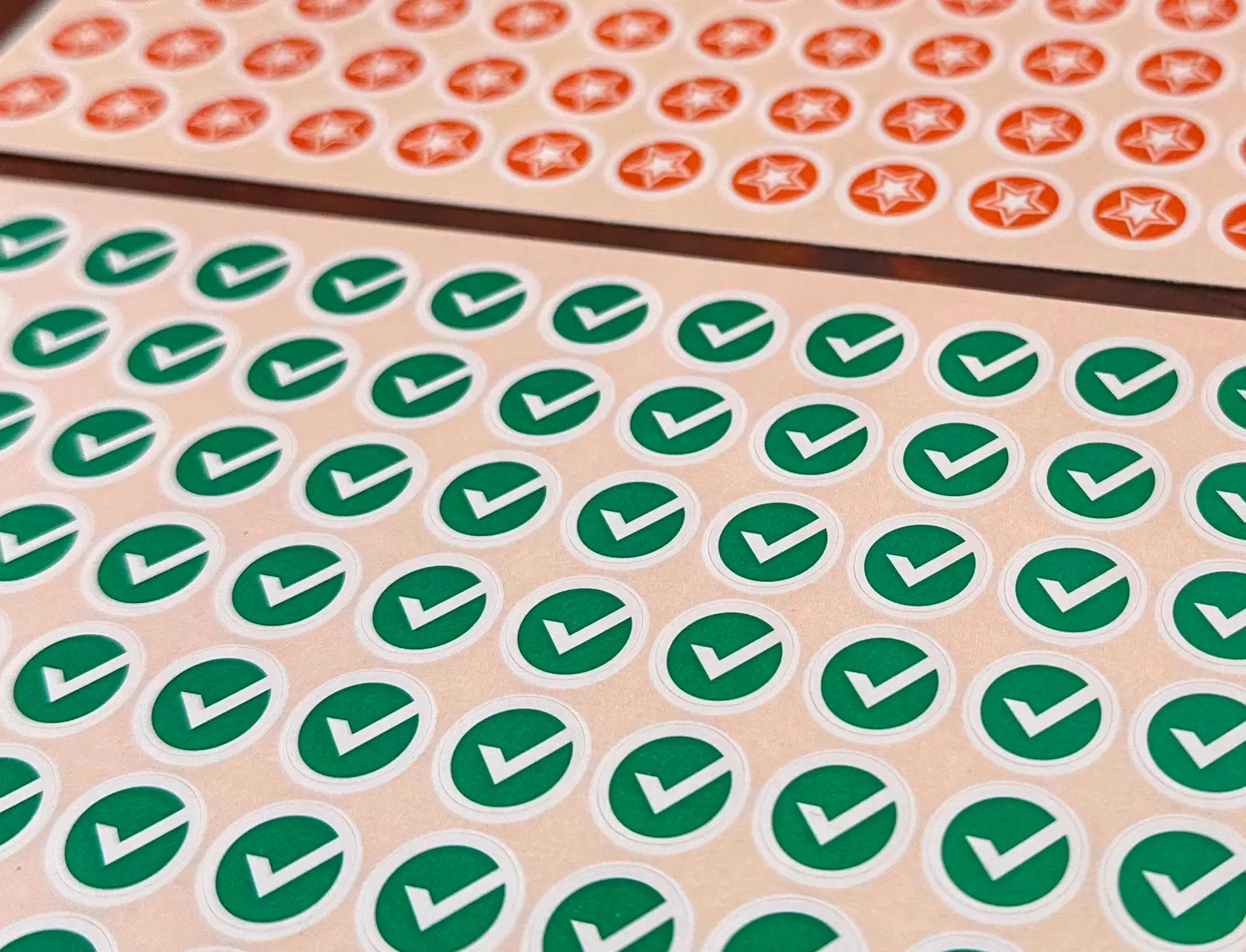 Hojas de stickers con check verdes y estrellas naranjas sobre la mesa